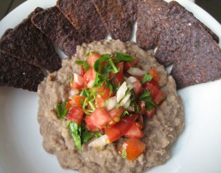 a close up of a plate of Refried Beans and blue tortilla chips