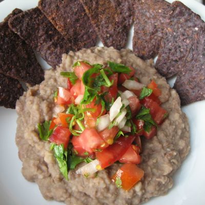 a close up of a plate of Refried Beans and blue tortilla chips