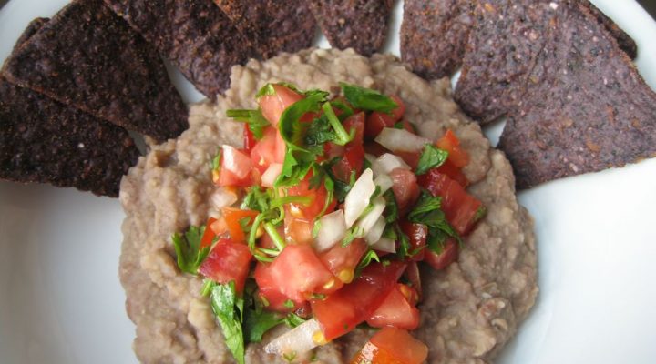 a close up of a plate of Refried Beans and blue tortilla chips