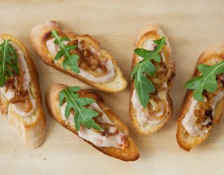 a close up of 5 white bean crostini on a cutboard