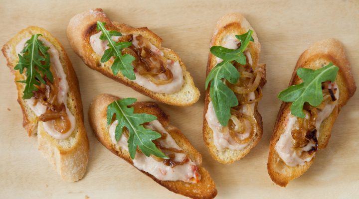 a close up of 5 white bean crostini on a cutboard