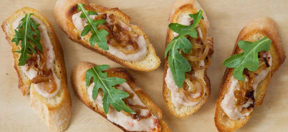 a close up of 5 white bean crostini on a cutboard