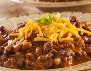 a close up of a bowl of slow cooker hearty bean, beef and sausage chili
