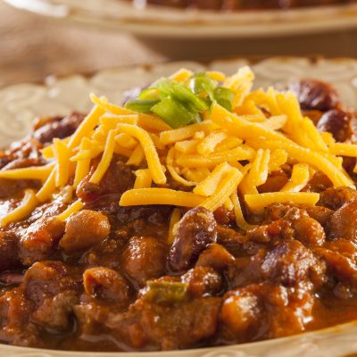 a close up of a bowl of slow cooker hearty bean, beef and sausage chili