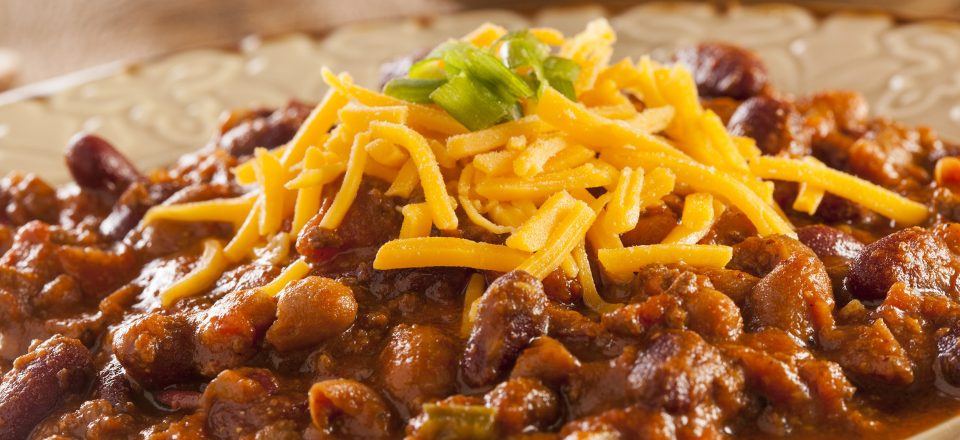 a close up of a bowl of slow cooker hearty bean, beef and sausage chili