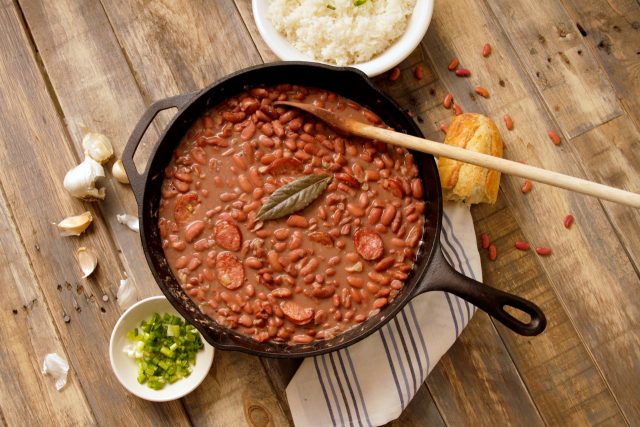 cast iron pot of red beans on table with wooden spoon