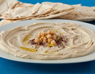 a bowl of Hummus next to some pita bread