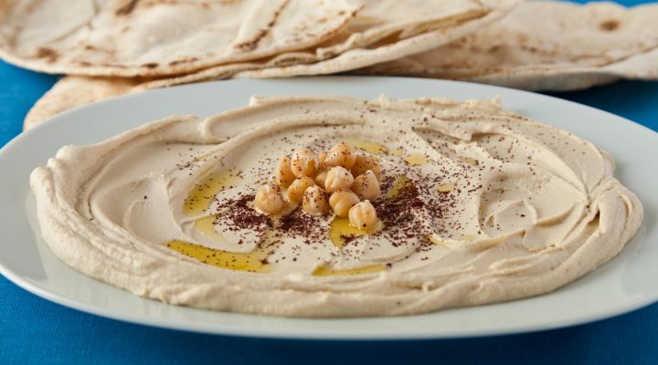 a bowl of Hummus next to some pita bread