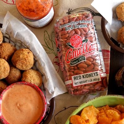 a tray of red beans and rice boudin balls with dipping sauce in a cup on the side, next to a package of camellia brand red kidneys