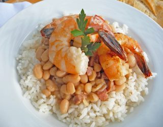 a close up of a plate of new orleans style white beans with a shrimp on top