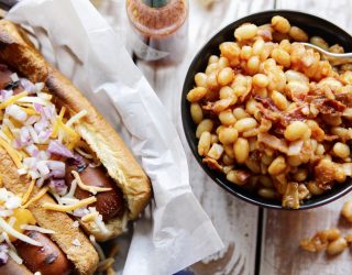 Chipotle Baked Beans in a bowl next to 2 grilled hot dogs