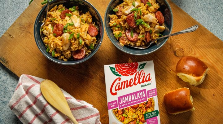 Gluten Free Cajun Jambalaya in 2 smal bowls next to a box of camellia brand cajun seasoning mix and 2 small bread rolls