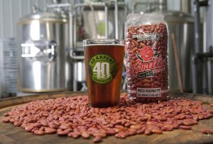 a glass of beer from 40 Arpent Brewing Company next to a package of camellia red beans, surrounded by a seas of red beans
