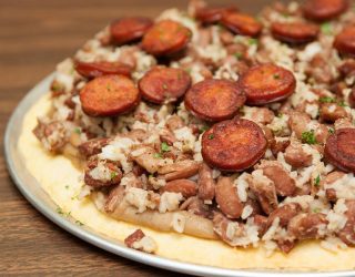 a close up of a red beans and rice with andouille pizza