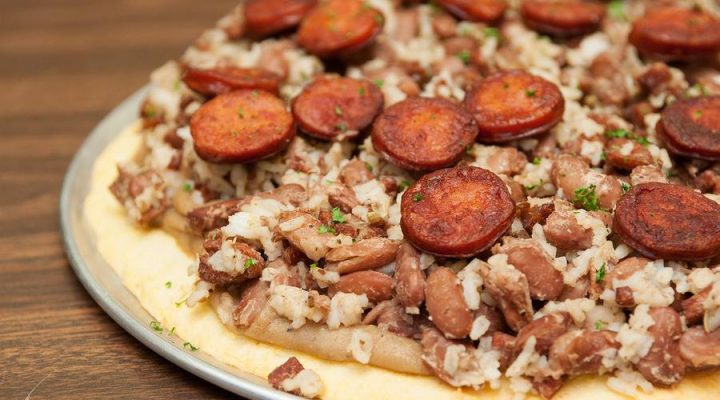 a close up of a red beans and rice with andouille pizza