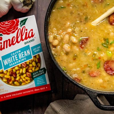 Stovetop Cajun White Beans in a dutch oven next to a box of cajun white bean seasoning