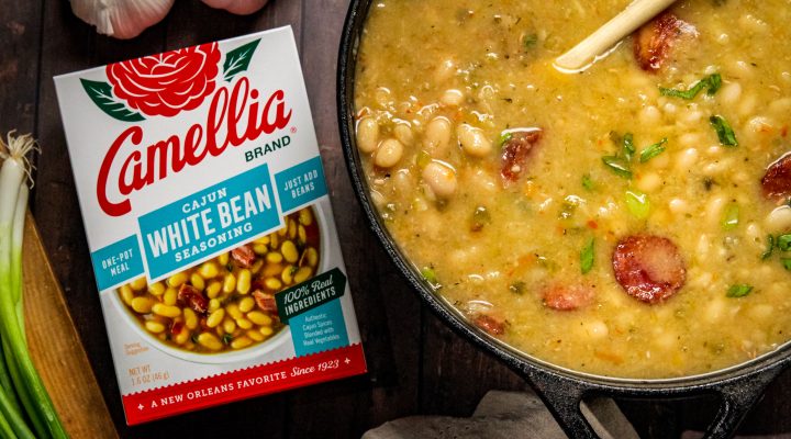 Stovetop Cajun White Beans in a dutch oven next to a box of cajun white bean seasoning