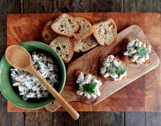 a bowl of Caesar-Style White Beans next to small pieces of bread with the beans on it