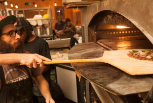 a chef putting a Red Beans and Rice Pizza into the stove