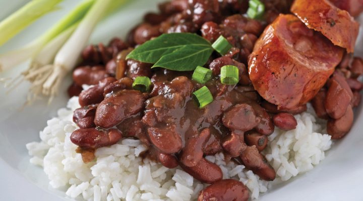 a close up of a plate of red beans and rice with green onions