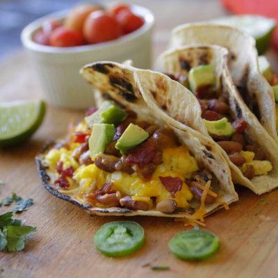 3 bacon and bean breakfast tacos on a cut board