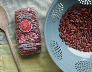 a close up of a package of red beans next to a strainer full of beans