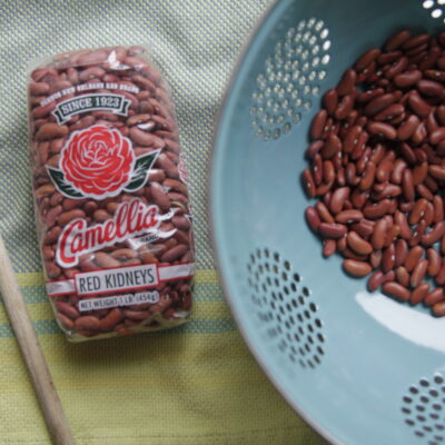 a close up of a package of red beans next to a strainer full of beans