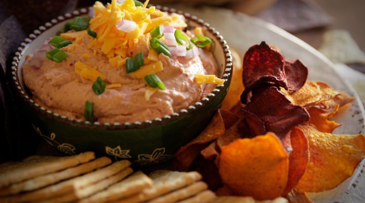 a close up of a plate of skinny red bean dip and a side of chips