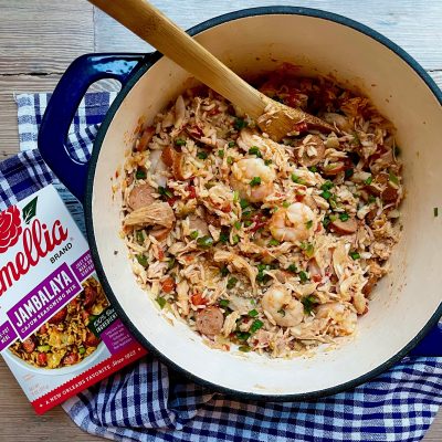 Blue dutch oven of Creole Jambalaya with Camellia Brand's Jambalaya Seasoning Mix next to it