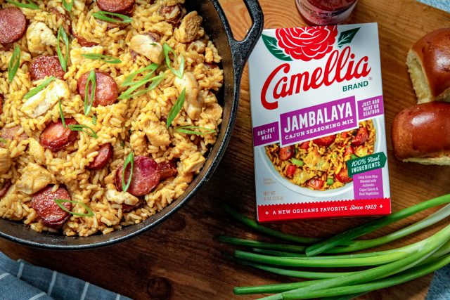 sausage and chicken jambalaya with dirty rice in a cast iron dutch oven with a box of camellia brand jambalaya seasoning mix