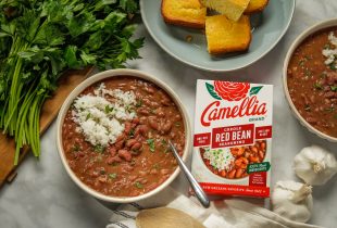 bowl of red beans and rice next to a bof of camellia brand creole red bean seasoning and a bowl of cornbread