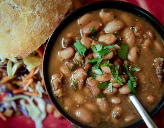 Slow Cooker Charro Beans with a cilantro garnish in a bowl with a side of bread and a salad