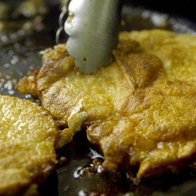 2 pork chops cooking in a skillet