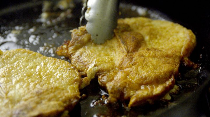 2 pork chops cooking in a skillet