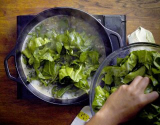 a chef adding collard greens to his pot that is cooking