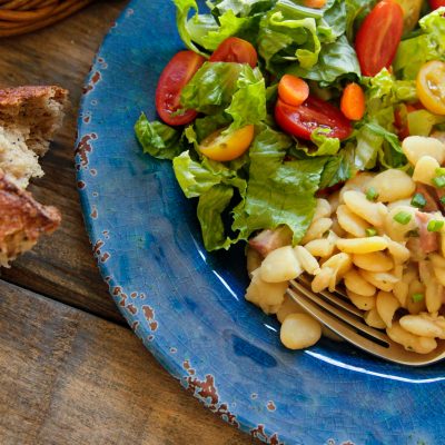 a plate of dorothy's delicious lima beans with a side salad and bread