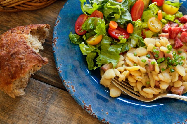 a plate of dorothy's delicious lima beans with a side salad and bread