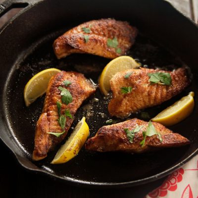 a cast iron pot with 4 pieces of golden sauteed catfish