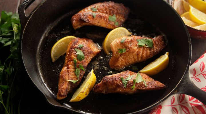 a cast iron pot with 4 pieces of golden sauteed catfish