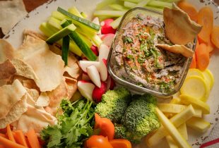 a close up of a dish of black bean hummus and various dipping snacks