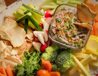 a close up of a dish of black bean hummus and various dipping snacks