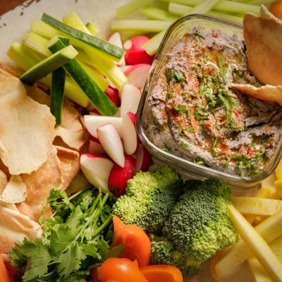 a close up of a dish of black bean hummus and various dipping snacks