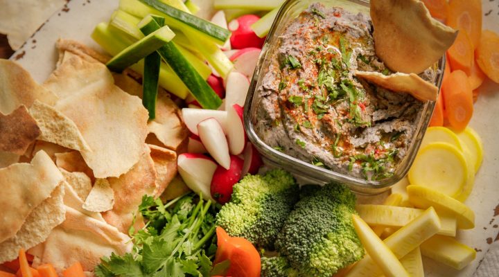 a close up of a dish of black bean hummus and various dipping snacks