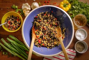 a mixing bowl filled with black bean quinoa salad waiting to be mixed