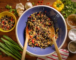 a mixing bowl filled with black bean quinoa salad waiting to be mixed