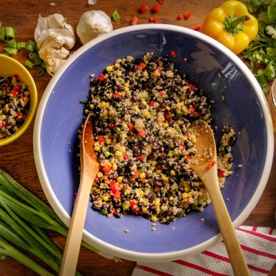 a mixing bowl filled with black bean quinoa salad waiting to be mixed