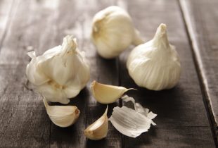 2 whole cloves of garlic next to a clove of garlic that has its cloves removed