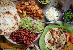 Place of tortillas, grilled shrimp, guacamole, red beans and cheese with topping on the side.