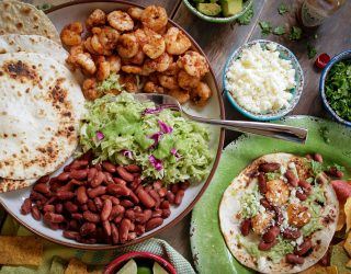 Place of tortillas, grilled shrimp, guacamole, red beans and cheese with topping on the side.