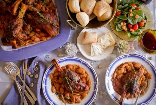 a big platter of lamb shanks butter beans next to 2 small plates of the lamb shanks